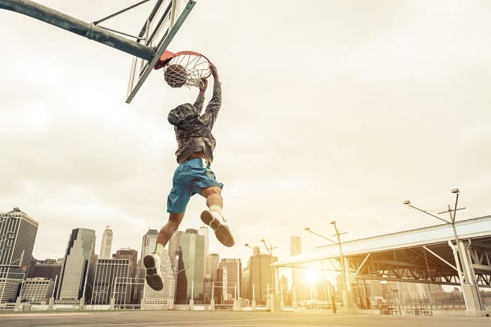 Basketball street player making a rear slam dunk. New york and Manhattan buildings in the background