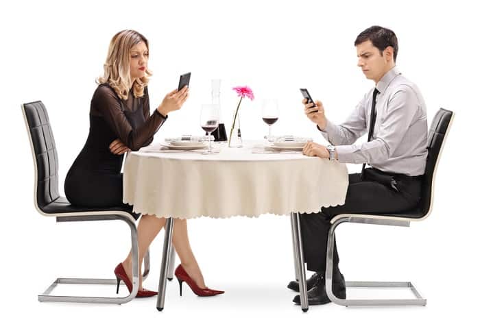 Man and woman at restaurant table and looking at phones