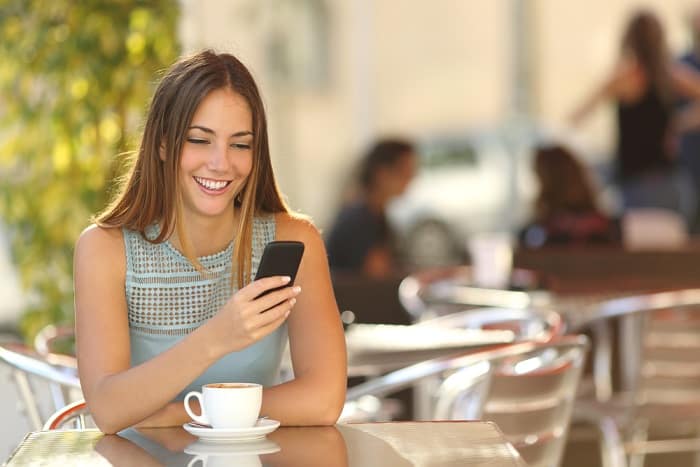 Girl texting on the smart phone in a restaurant terrace with an unfocused background