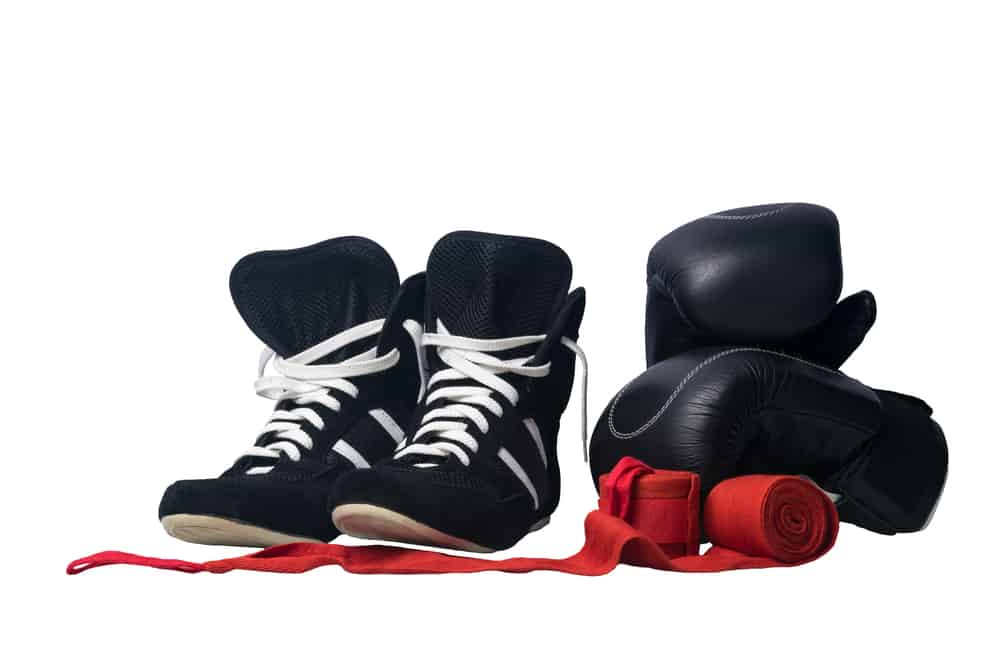 black wrestling shoes, black boxing gloves and unwound red protective bandages for martial arts isolated on a white background