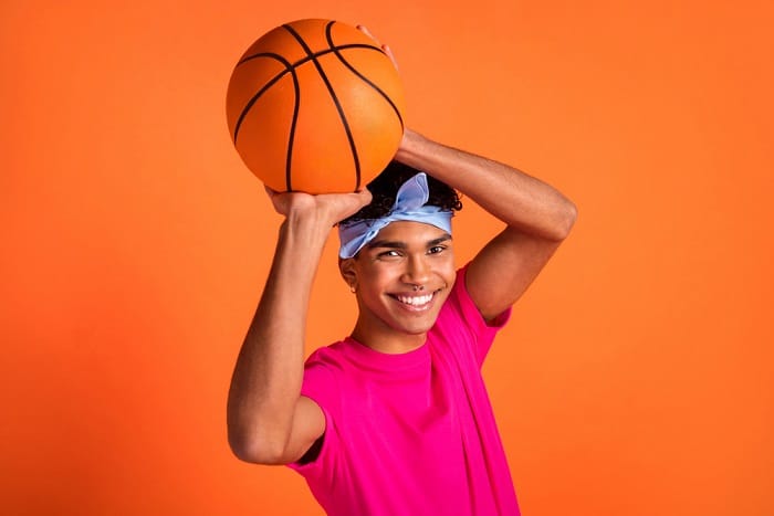High angle view photo young hipster smiling playing throwing ball wearing piercing isolated on vivid orange color background