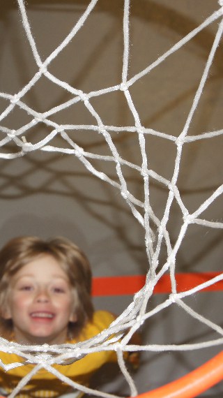 kid smiling below a basketball hoop