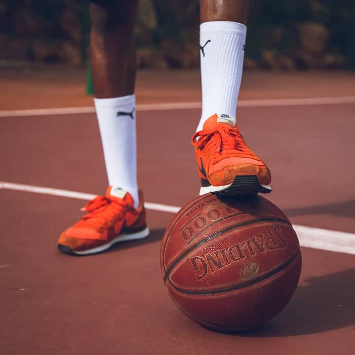 Legs of basketball player with socks and basketball under his shoe