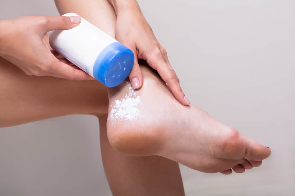 Close-up Of Woman Applying Powder To Her Foot