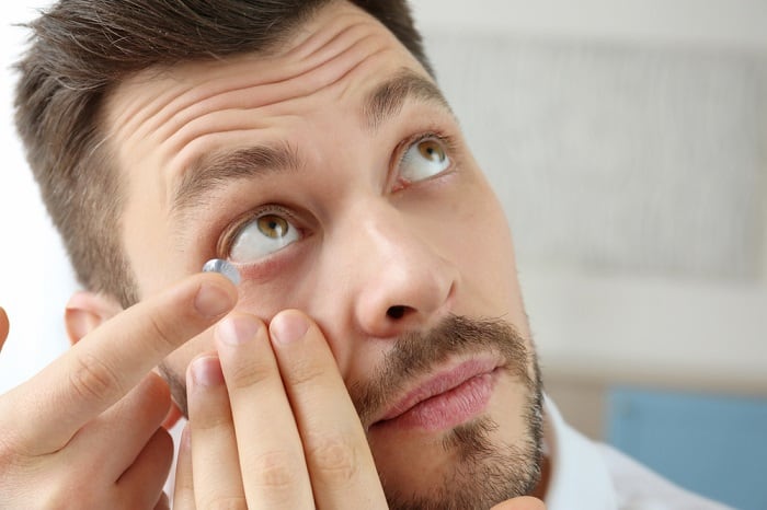Young man putting contact lenses at home.